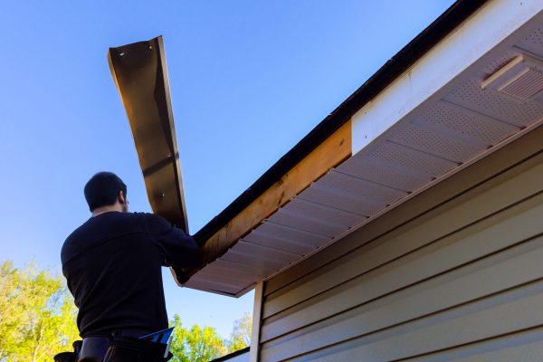 Master makes repairs after hurricane has caused aluminum fascia trim to blow off, exposing exposed wood